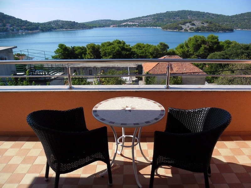 Balcone con tavolo rotondo e due poltroncine in vimini sopra l'acqua
