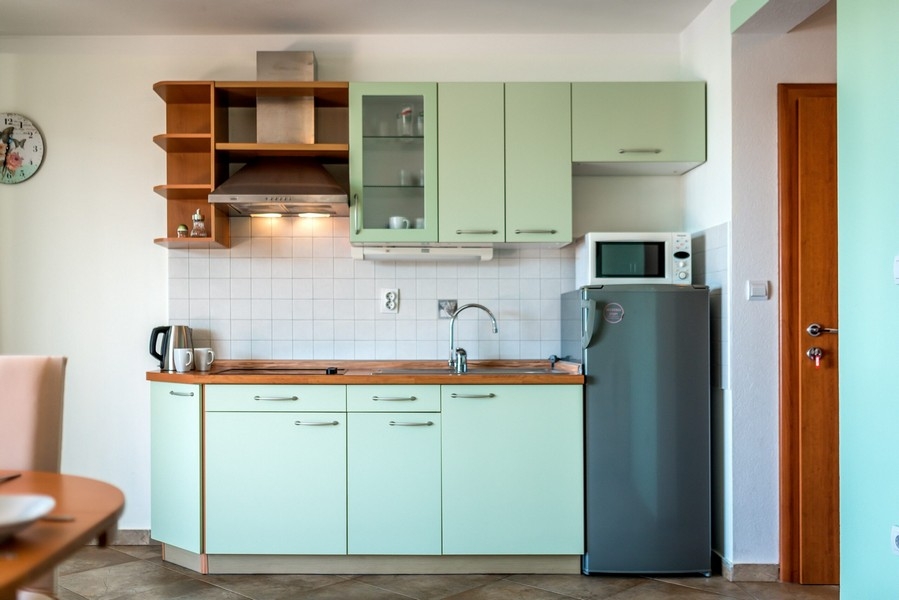 Angolo cottura verde menta con piano di lavoro in legno