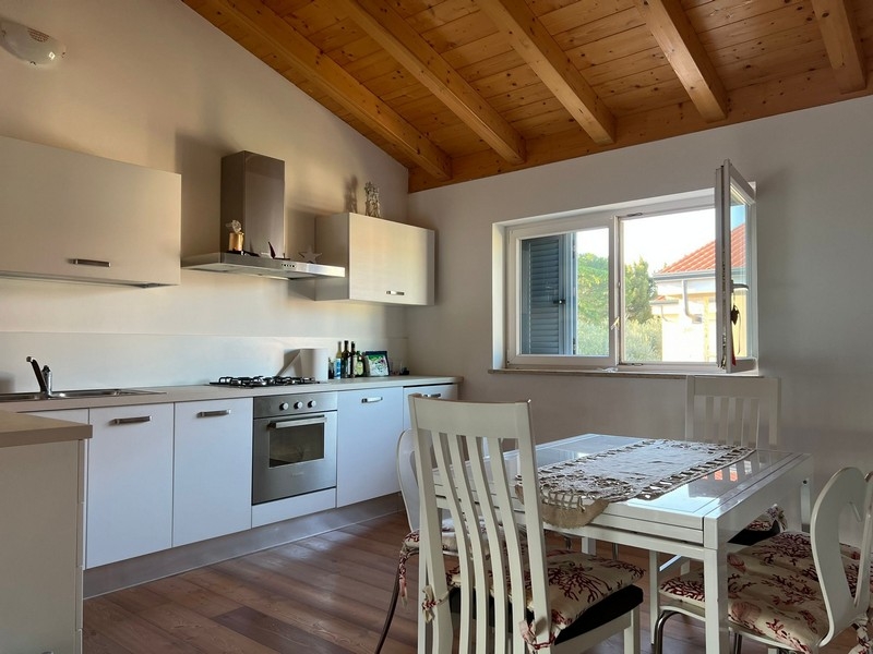 Cucina con zona pranzo e soffitto a travi in legno a vista