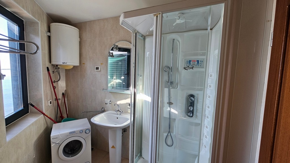 Bagno con doccia, lavatrice e finestra