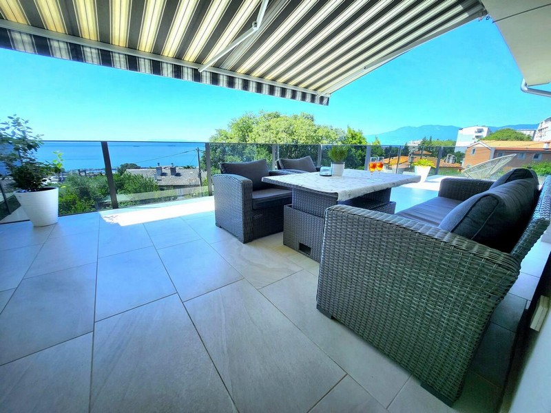 Terrazza con tenda da sole, mobili in rattan e parapetto in vetro