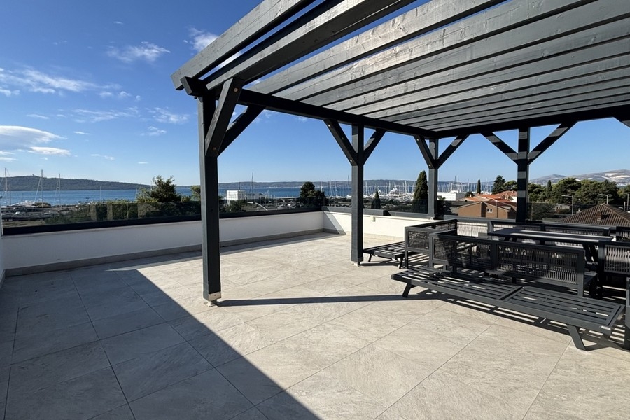 Terrazza sul tetto sotto una pergola in legno scuro con vista sul porto