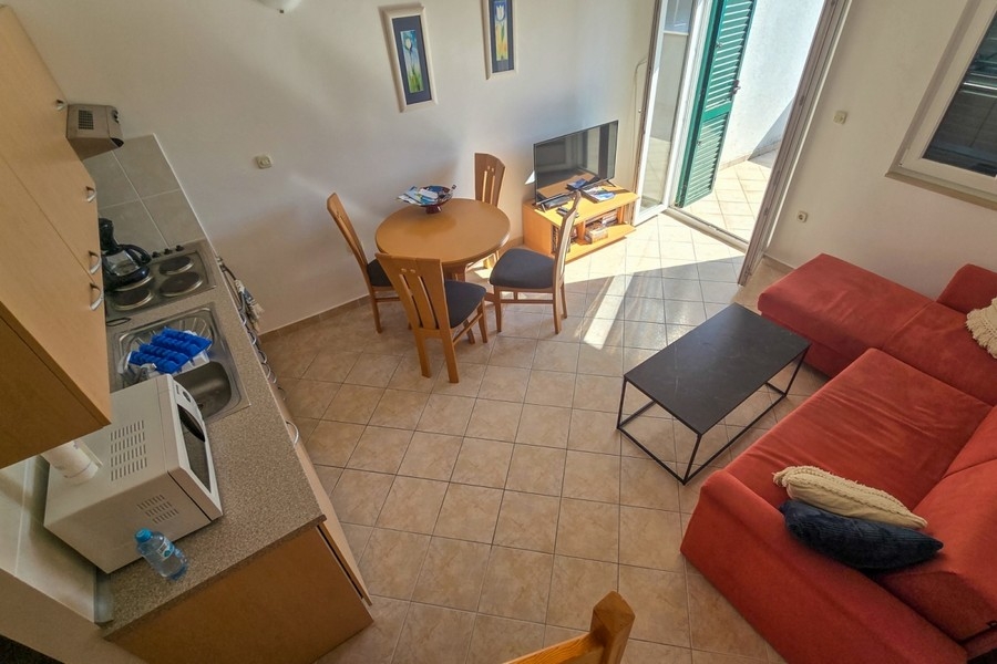 Zona giorno luminosa con cucina aperta e accesso al balcone