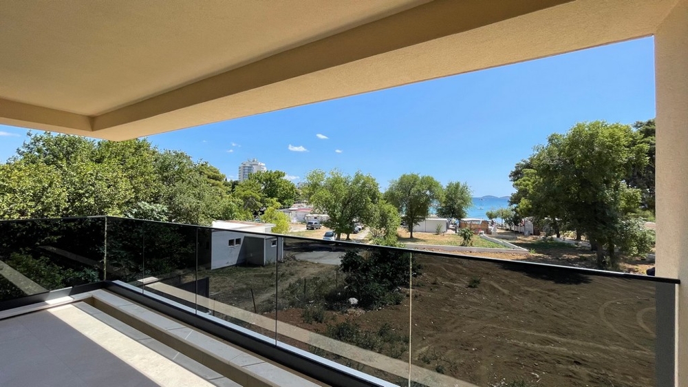Balcone con parapetto in vetro e vista attraverso gli alberi sulla spiaggia