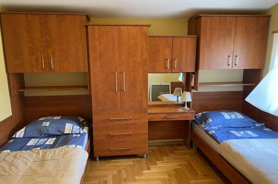 Camera da letto con letti singoli e mobili in legno in un appartamento vacanze