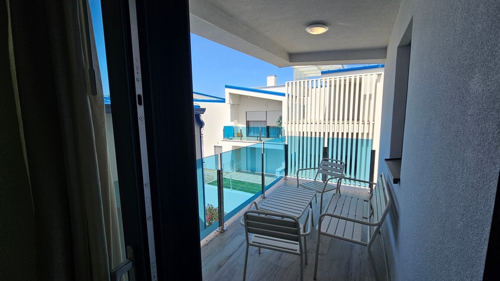 Balcone coperto con parapetto in vetro e zona salotto
