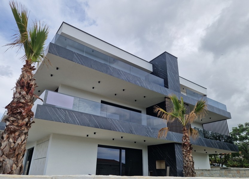 Casa con parapetti in marmo scuro e palme davanti