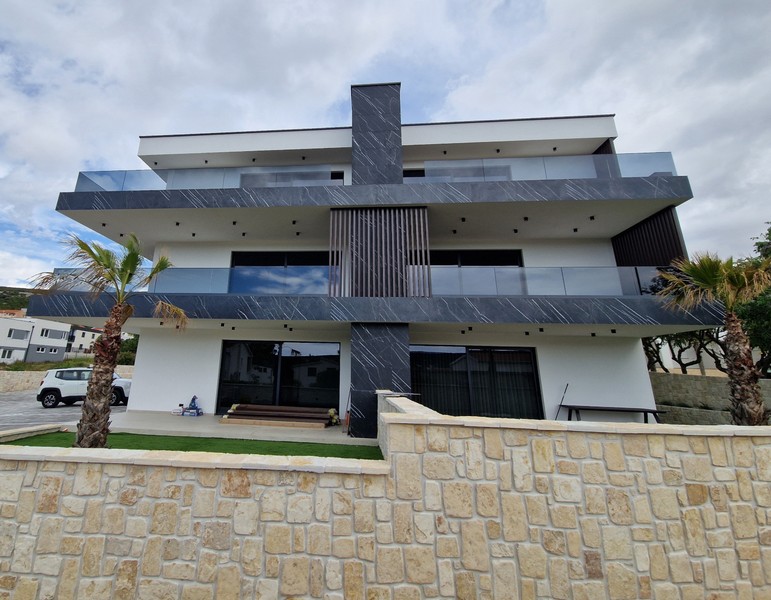 Edificio nuovo moderno con parapetti in vetro e muro in pietra naturale a Stara Novalja, Isola di Pag