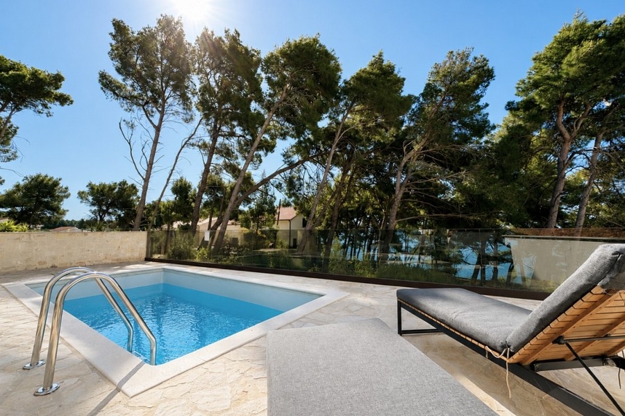 Area della piscina con lettini e vista sul paesaggio costiero