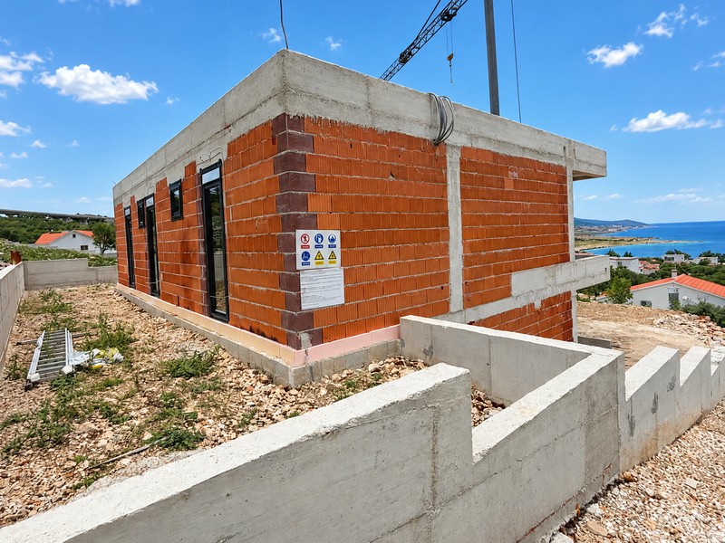 Grezzo con finestre installate, cartelli di cantiere e muri in cemento