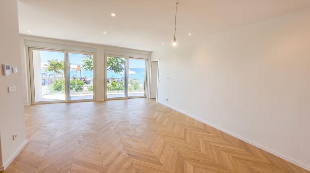 Zona giorno luminosa con parquet a spina di pesce e vista mare