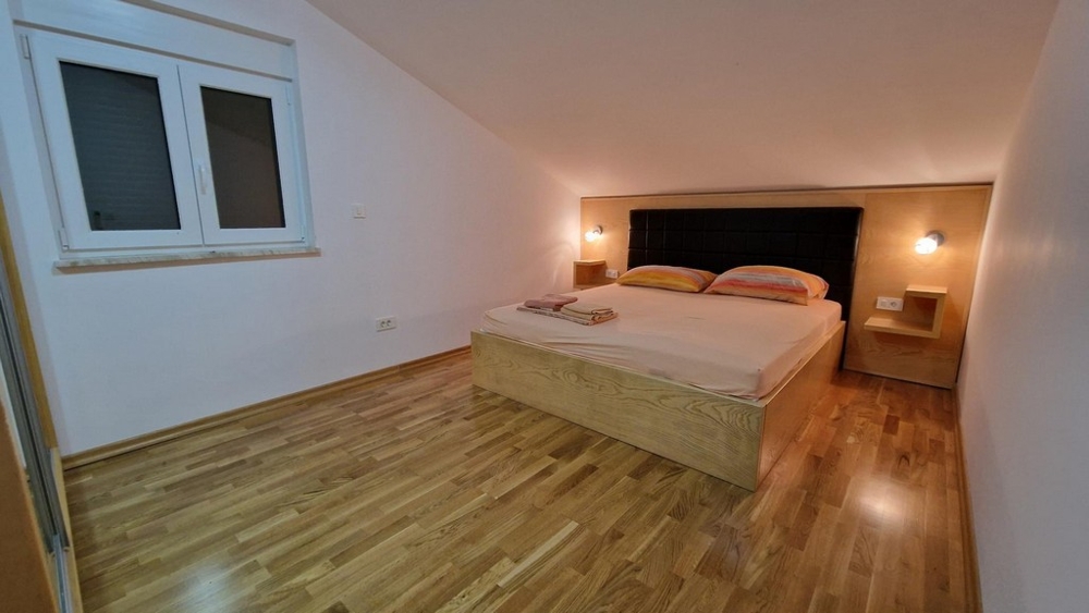 Camera da letto con letto matrimoniale e pavimento in legno a Njivice su Krk