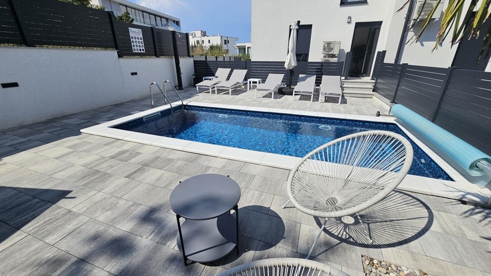 Piscina riscaldata con lettini nel giardino dell'appartamento a Malinska su Krk