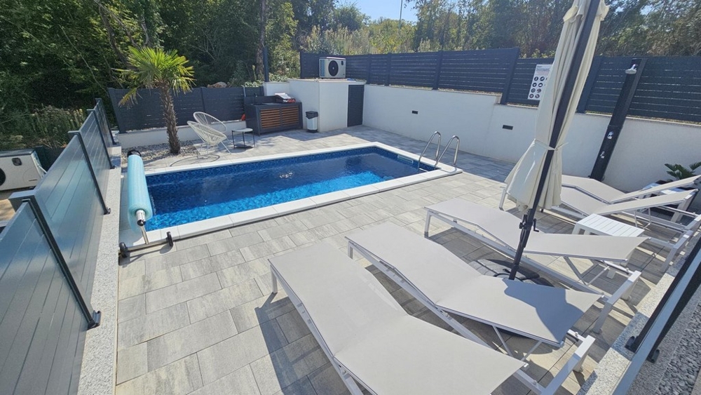 Piscina e solarium nel giardino privato dell'appartamento a Malinska
