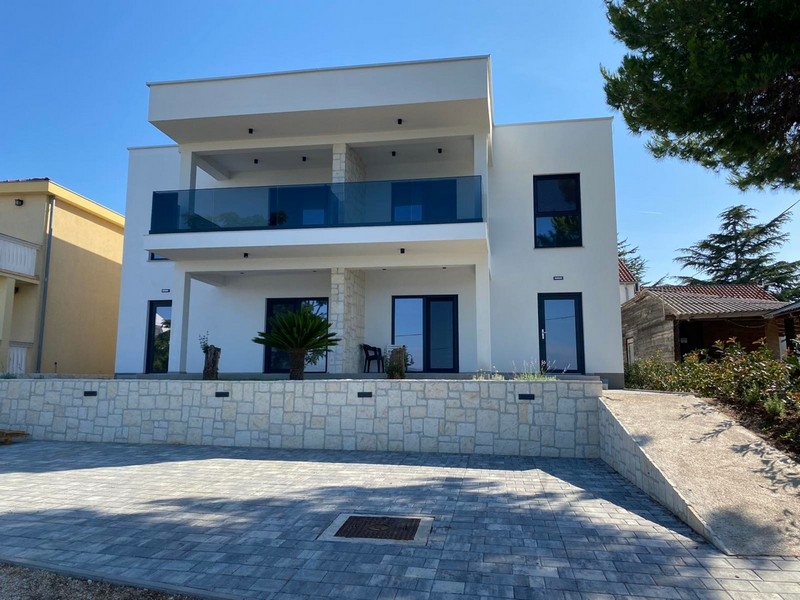 Vista frontale della villa con terrazza e posti auto