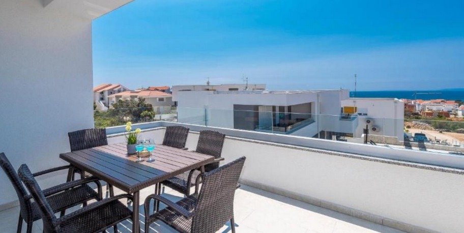 Terrazza coperta con tavolo da pranzo e vista su Novalja