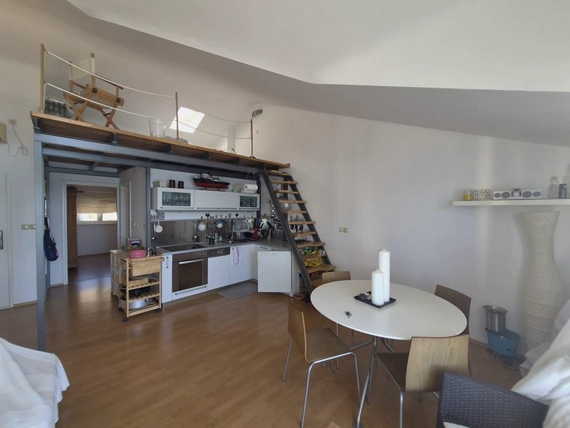 Zona giorno aperta con cucina e soppalco sotto il tetto