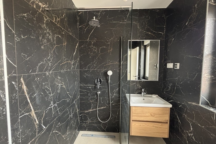 Bagno con doccia walk-in e lavabo in legno
