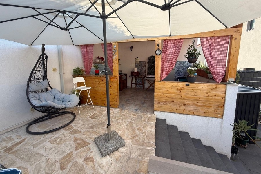 Cucina estiva con angolo salotto e sedia sospesa in giardino