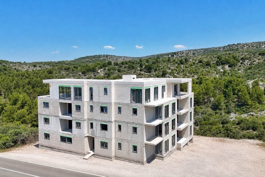 Nuovo edificio a quattro piani davanti a colline boscose