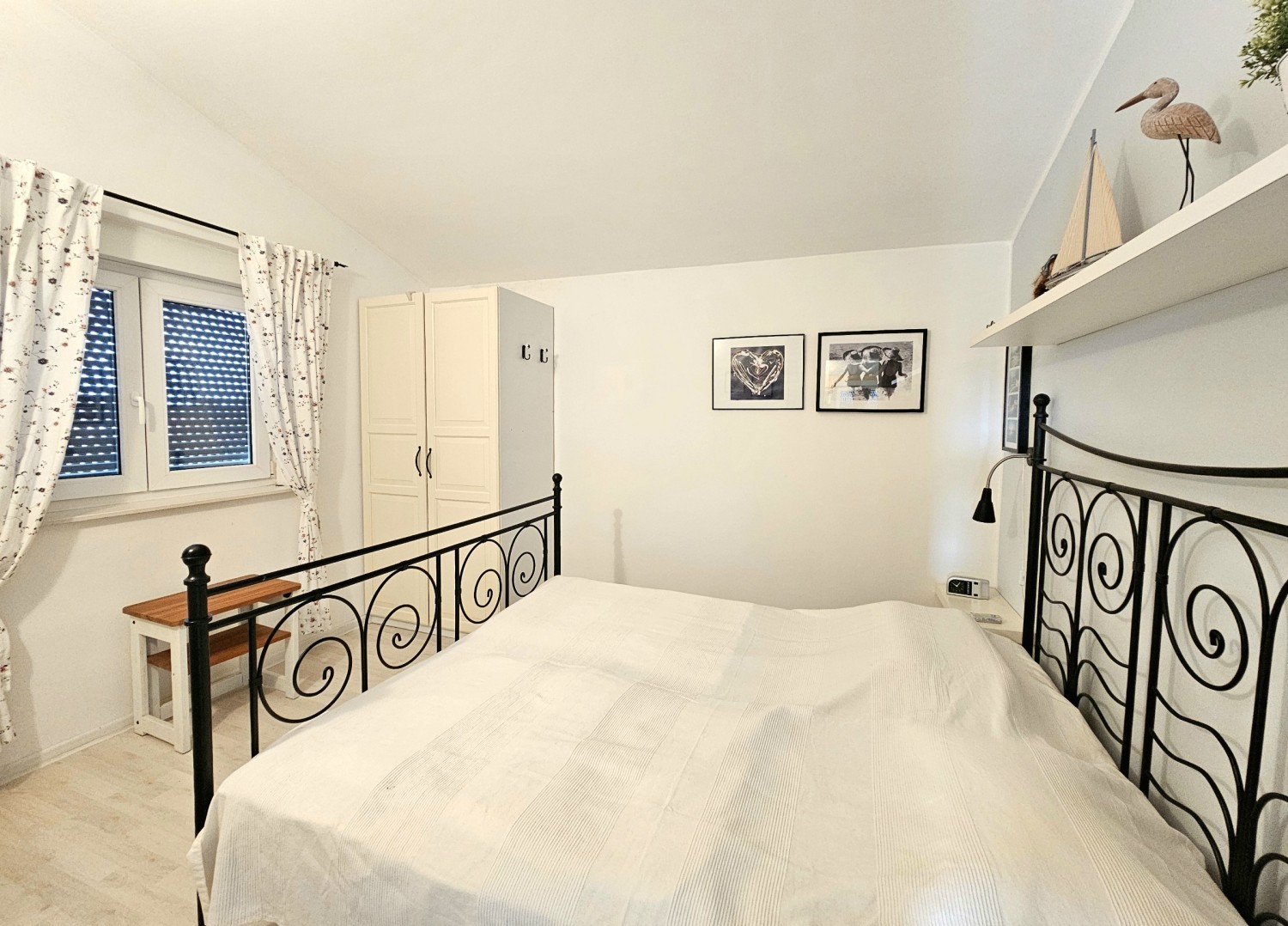 Camera da letto con letto matrimoniale in metallo sotto il soffitto spiovente