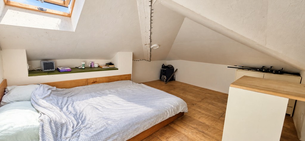 Camera in mansarda con letto sotto il soffitto spiovente