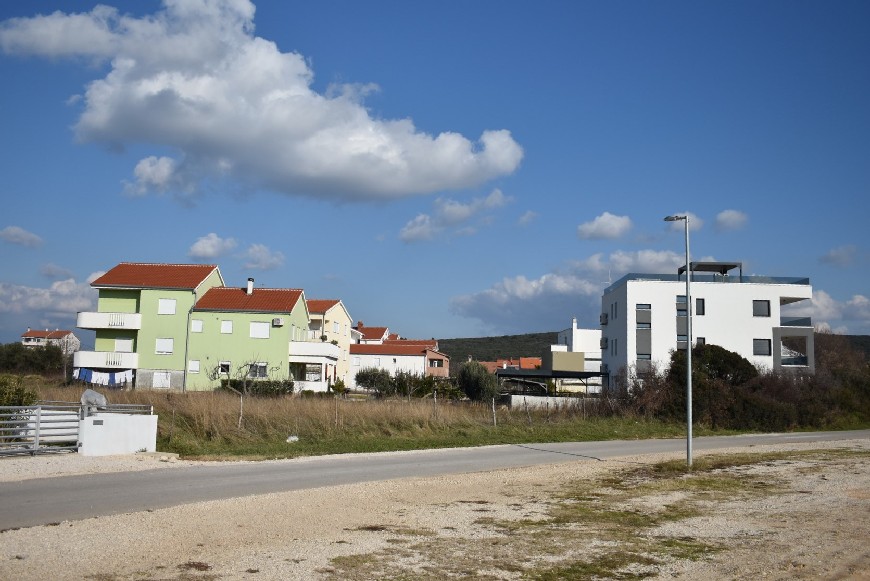 Vista sulla strada di accesso, sul terreno e sulle case vicine