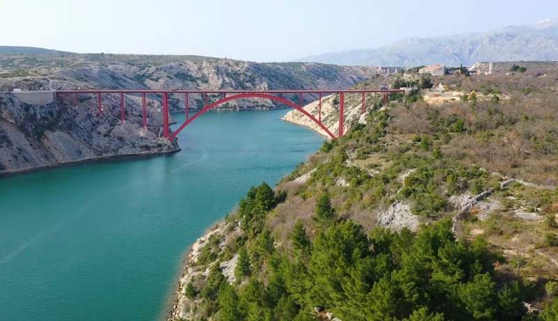 Ponte ad arco rosso sul canale tra pendii rocciosi