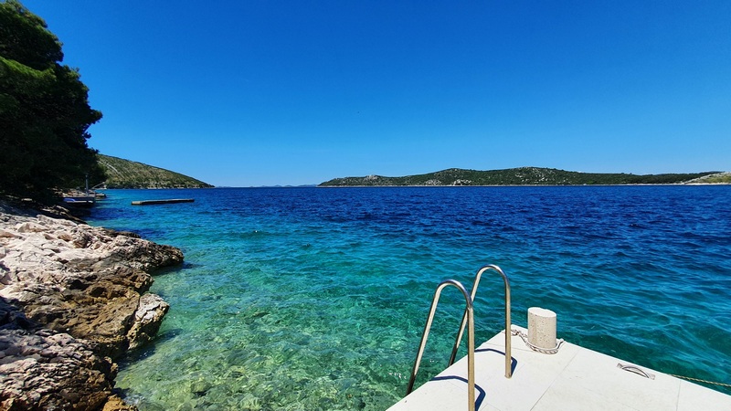 Piattaforma per il bagno con scaletta sull'acqua limpidissima