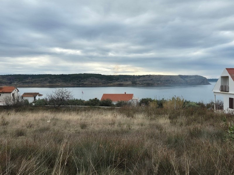 Erba secca con vista sulla baia sotto nuvole grigie