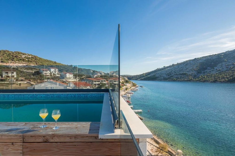 Bicchieri a bordo piscina con vista sul canale fino al pendio
