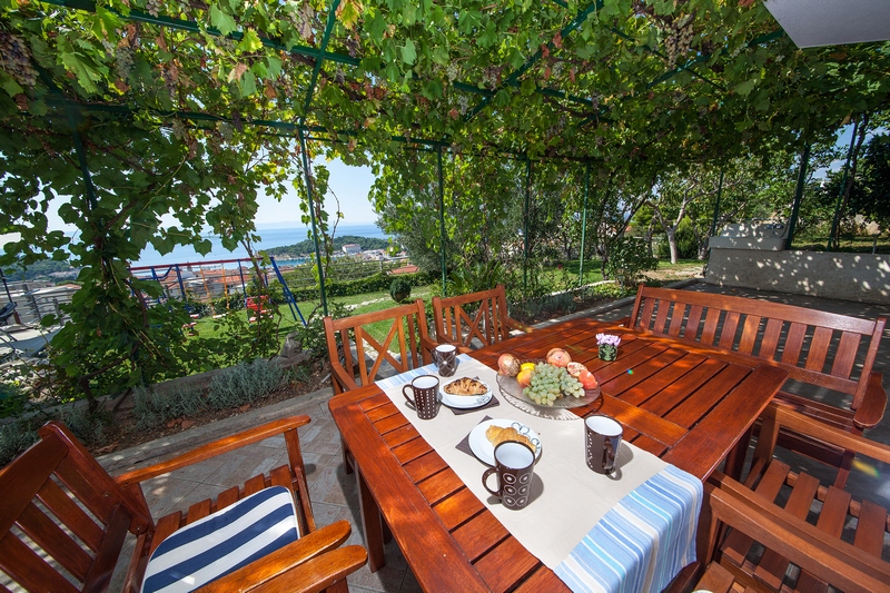 Terrazza ombreggiata con zona pranzo nel giardino della villa.