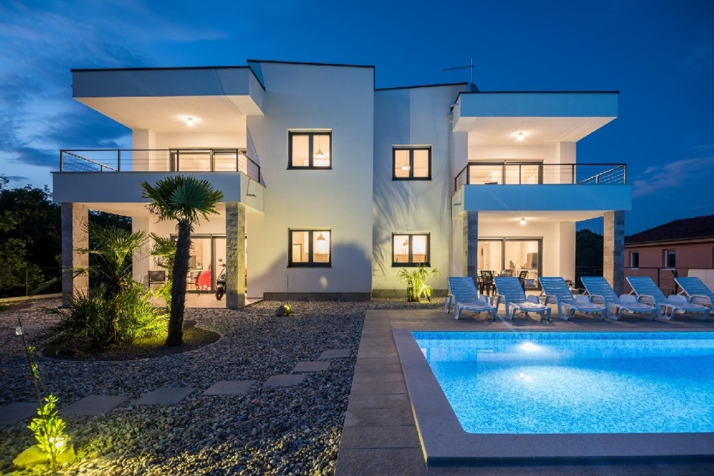 Villa illuminata con piscina e lettini al crepuscolo