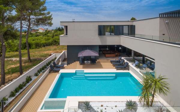 Piscina con deck in legno e ombrellone davanti alla villa