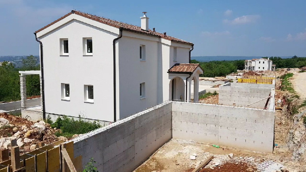 Casa bianca con tetto di tegole dietro il muro di sostegno in cemento