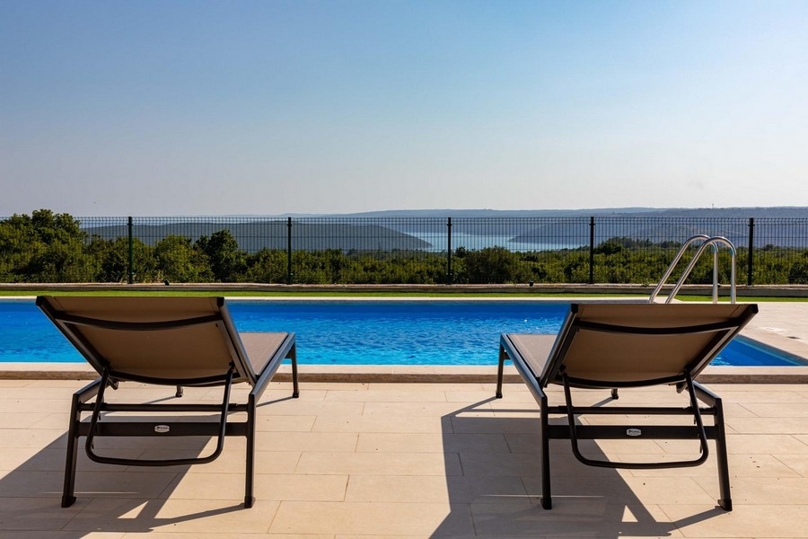 Due lettini a bordo piscina con vista sulla macchia fino alla baia