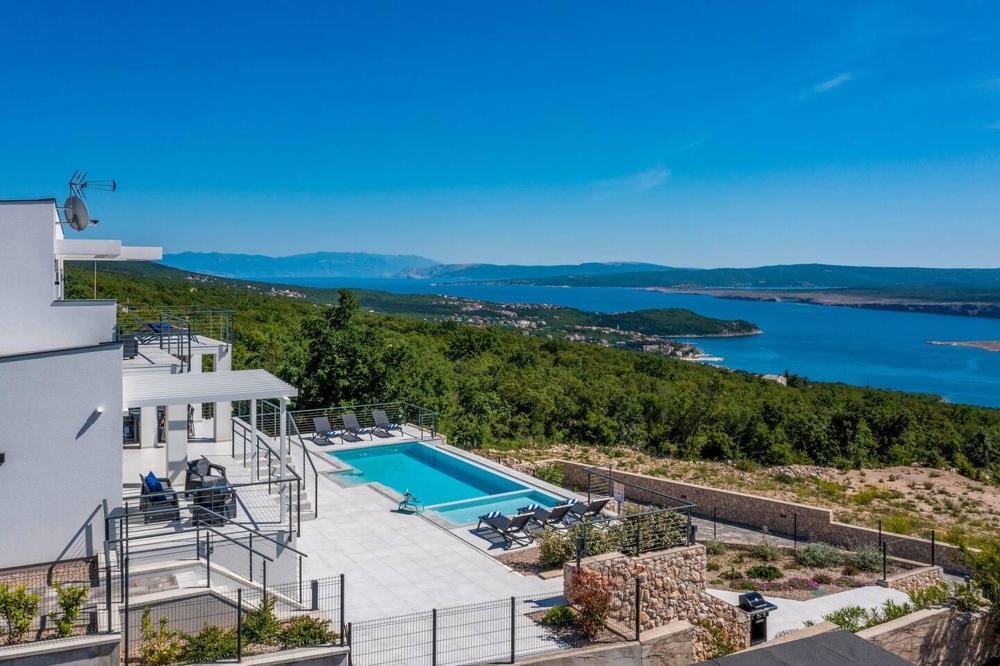 Piscina con lettini e ampia vista sulla macchia e sulla baia