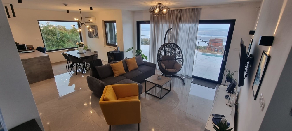Zona giorno aperta con sedia sospesa e vista sul mare