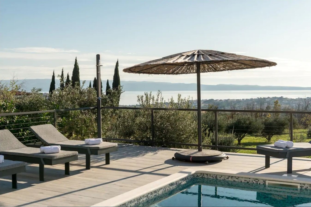 Piscina con lettini e ombrellone sopra la baia di Split