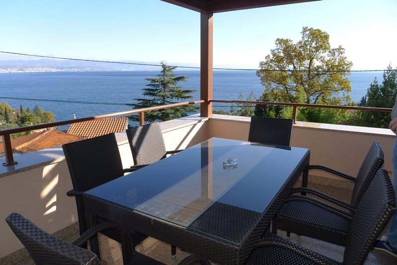 Terrazza coperta con tavolo in vetro e vista sulla baia