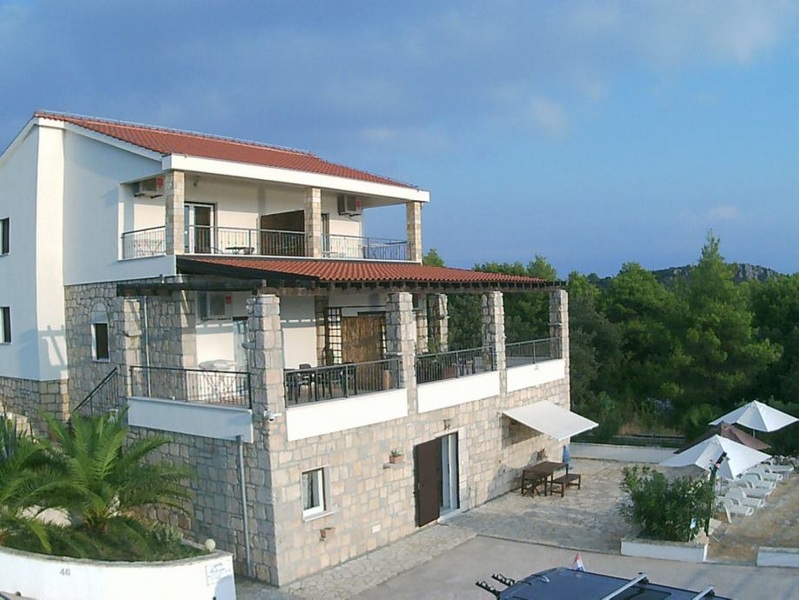 Casa con facciata in pietra naturale e terrazze su più lati