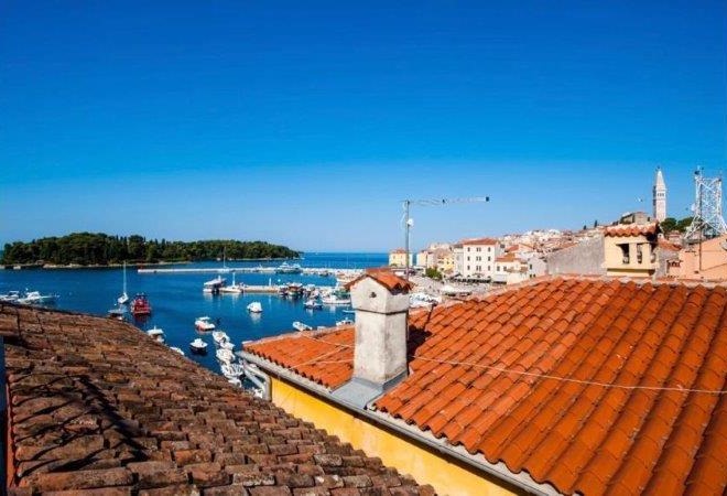 Tetti di tegole in primo piano e porto con campanile dietro