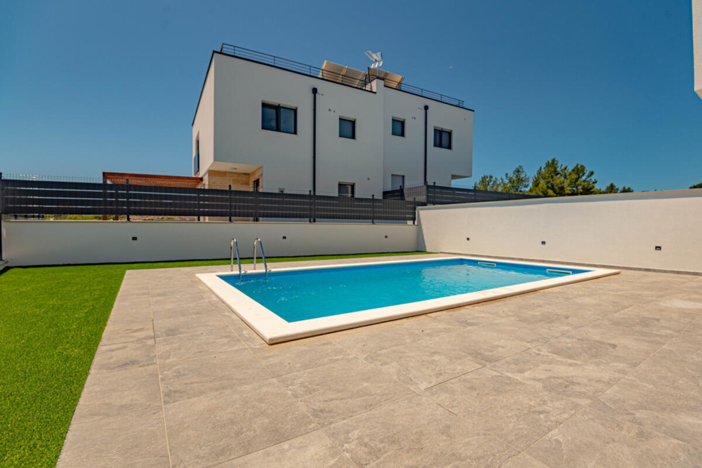 Piscina in giardino davanti alla casa bifamiliare bianca