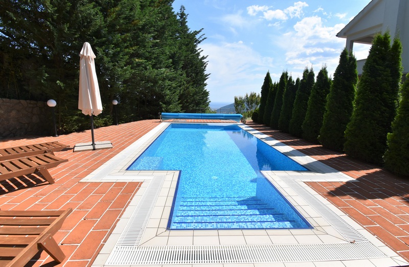 Piscina con ombrellone e cipressi sul bordo