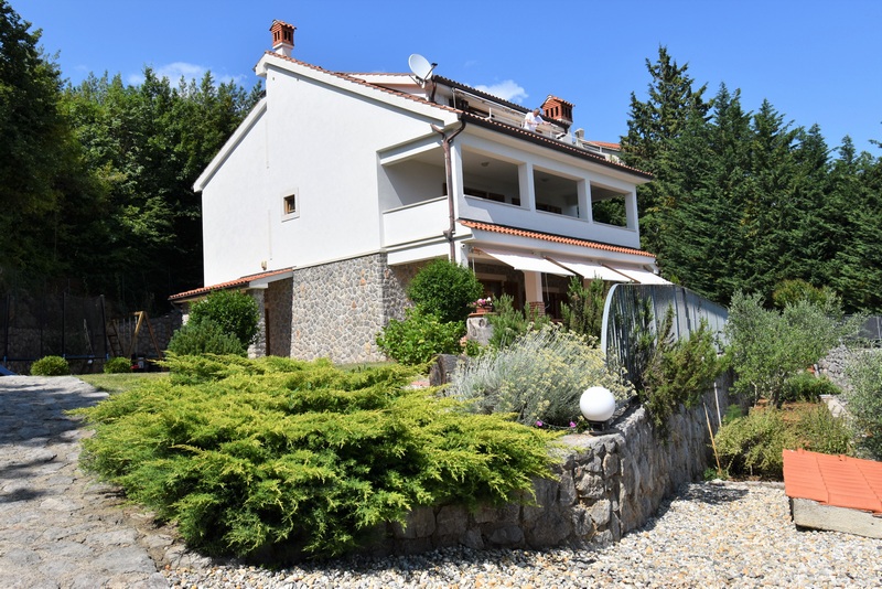 Casa bianca con loggia dietro cespugli di bosso e muro a secco
