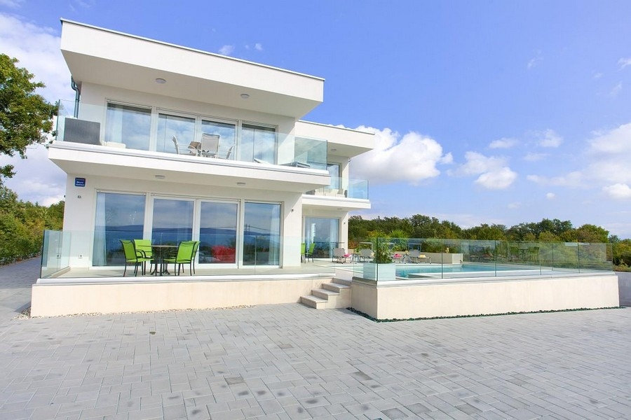 Villa bianca con ringhiere in vetro e piscina dietro una parete di vetro