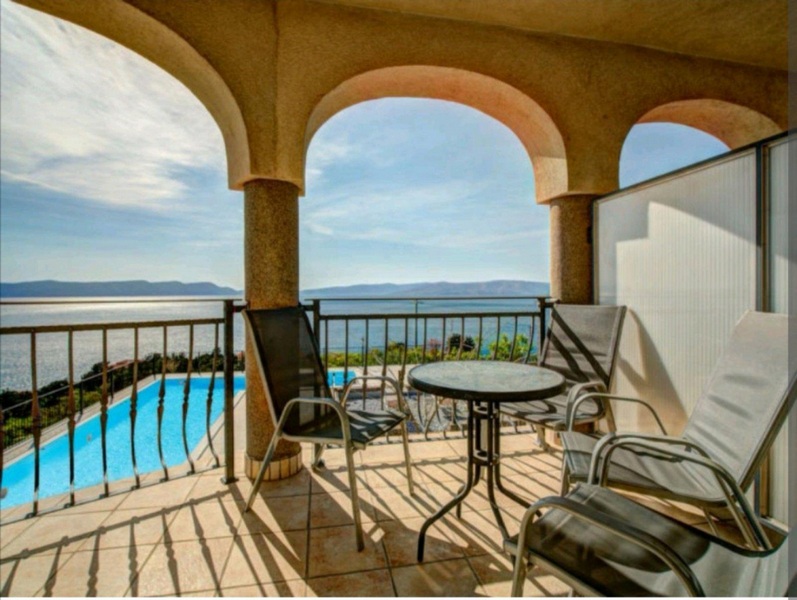 Vista su piscina e mare dalla terrazza coperta al piano superiore.