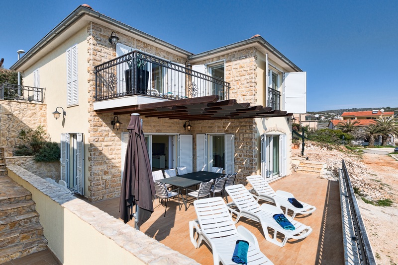 Casa con facciata in pietra naturale e lettini sulla terrazza