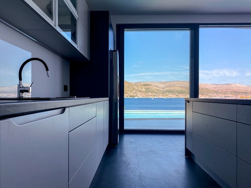 Cucina componibile bianca con porta aperta sulla terrazza della piscina