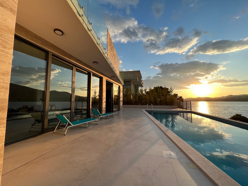 Piscina e lettini lungo la vetrata nella luce della sera
